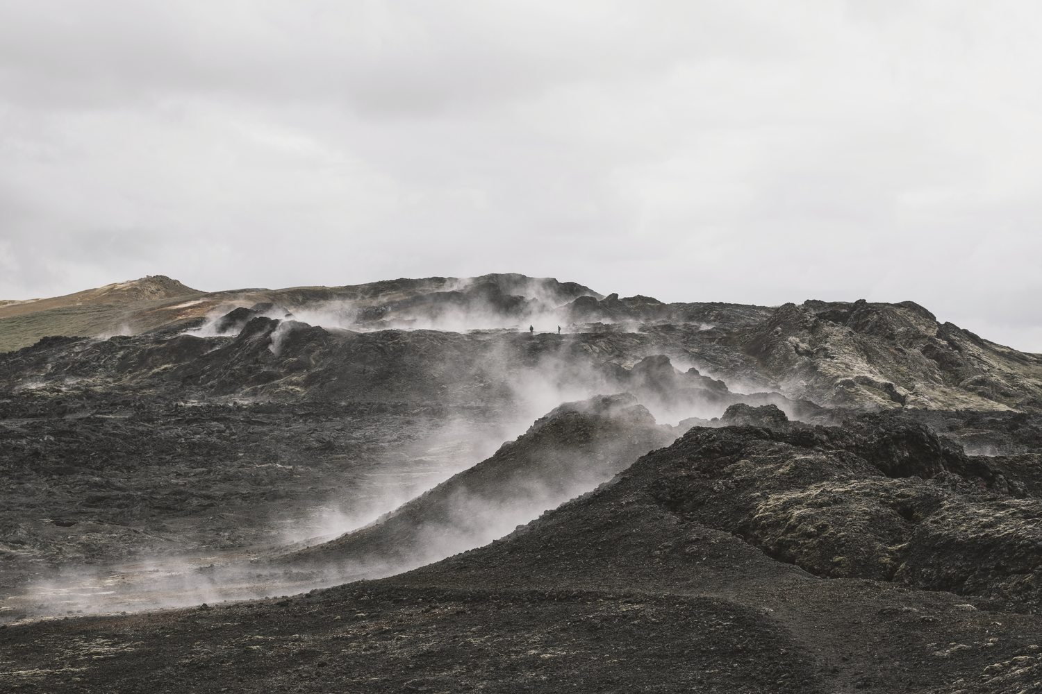 Vapor subindo entre a lava negra e o musgo na Islândia
